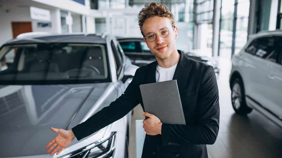 Ein Verkäufer zeigt auf ein Auto und erklärt dem Kunden die Konditionen beim Auto verkaufen Freiberg